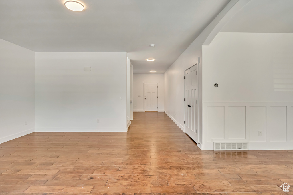 Unfurnished room featuring light wood finished floors, a decorative wall, and wainscoting