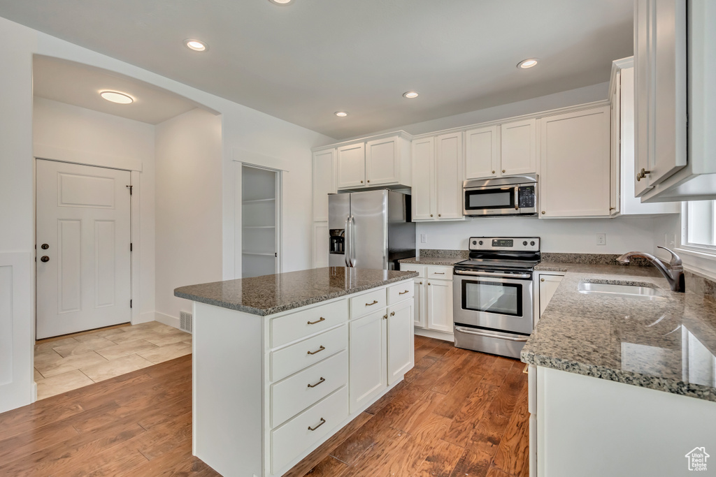 Kitchen with stainless steel appliances, a sink, dark wood finished floors, dark stone counters, and recessed lighting