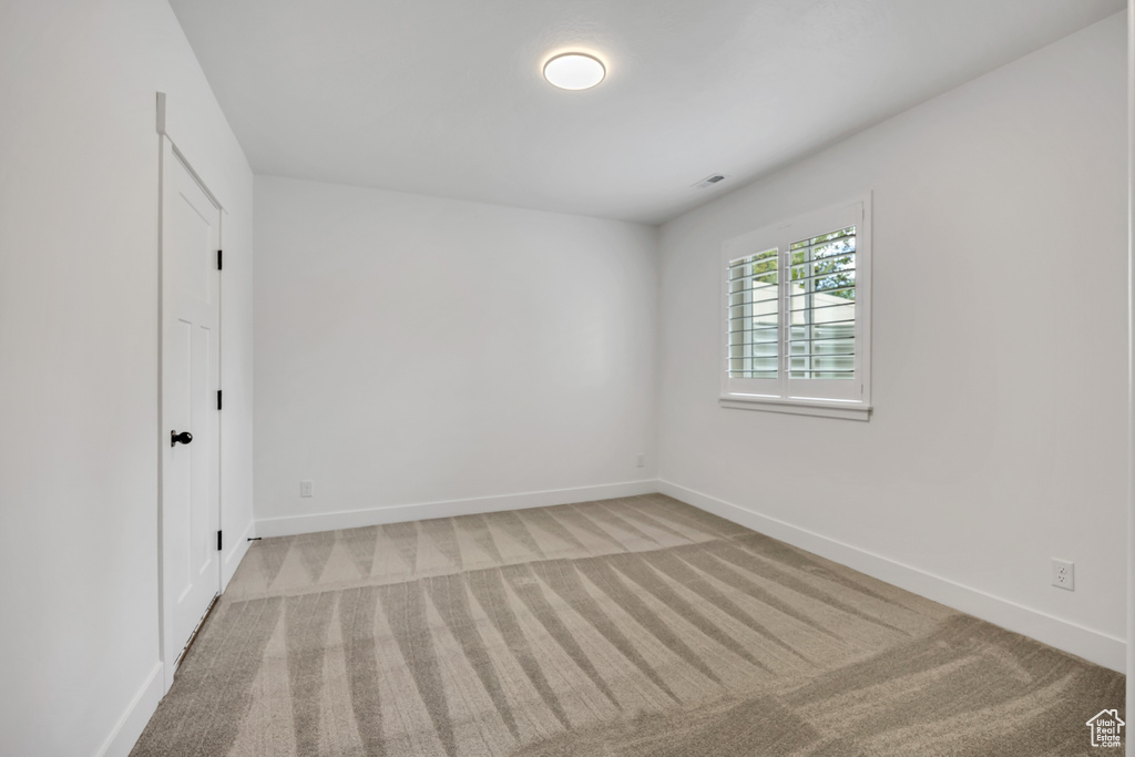 Unfurnished bedroom featuring light carpet and baseboards