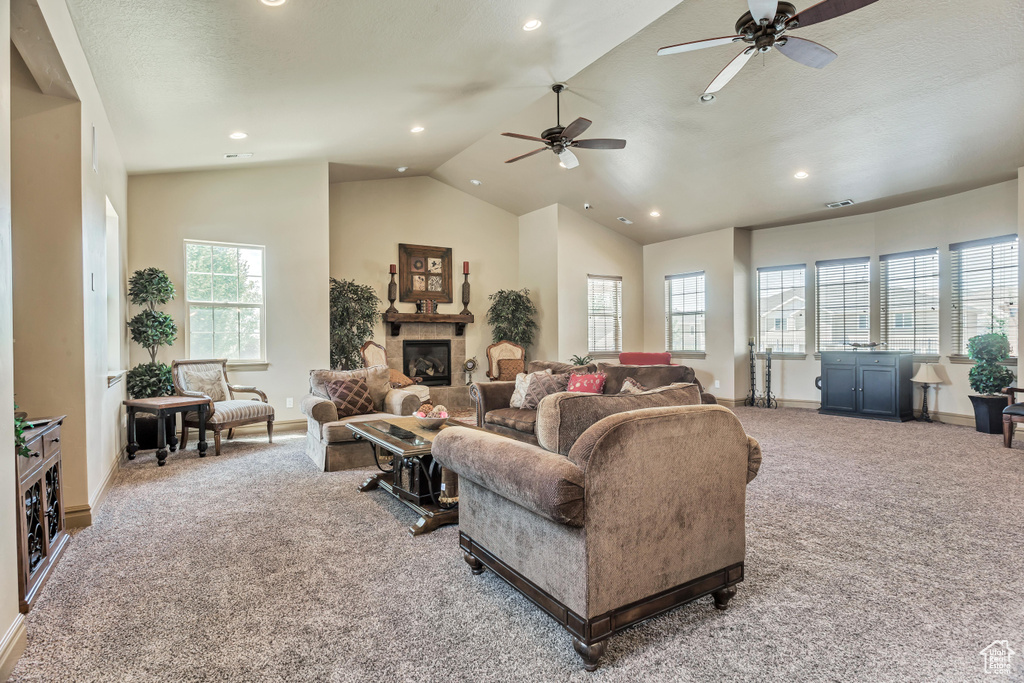 Carpeted living area featuring lofted ceiling, ceiling fan, recessed lighting, a glass covered fireplace, and baseboards