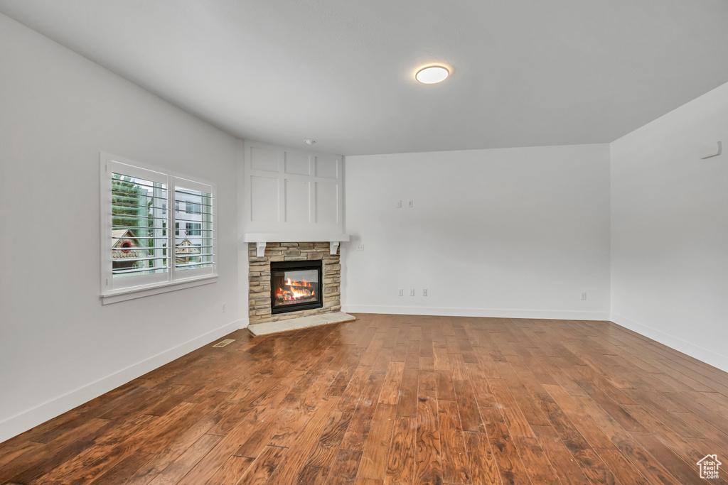 Unfurnished living room with hardwood / wood-style flooring, a fireplace, and baseboards