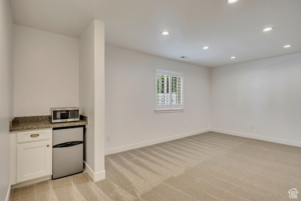 Kitchen featuring refrigerator, stainless steel microwave, light colored carpet, baseboards, and recessed lighting