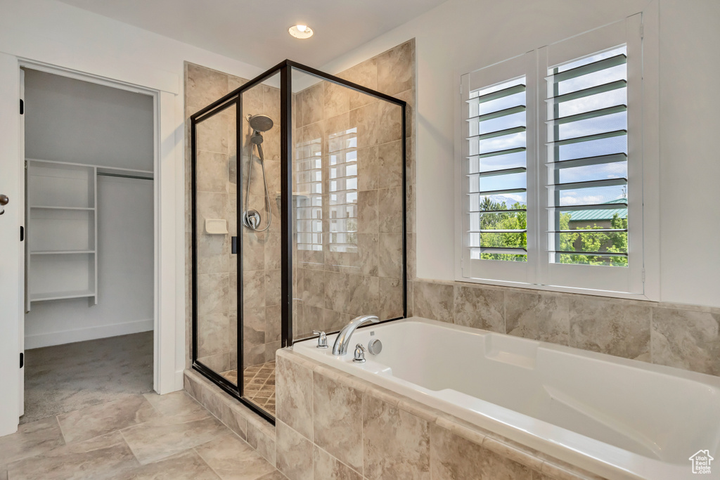 Bathroom with a shower stall, a bath, and a walk in closet