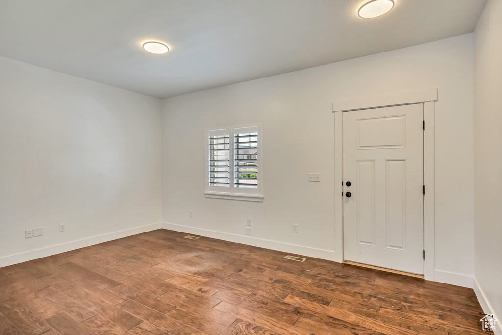 Spare room with baseboards and dark wood-style flooring