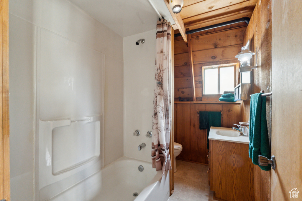 Full bathroom with vanity, toilet, shower / bathtub combination with curtain, tile patterned flooring, and wood walls
