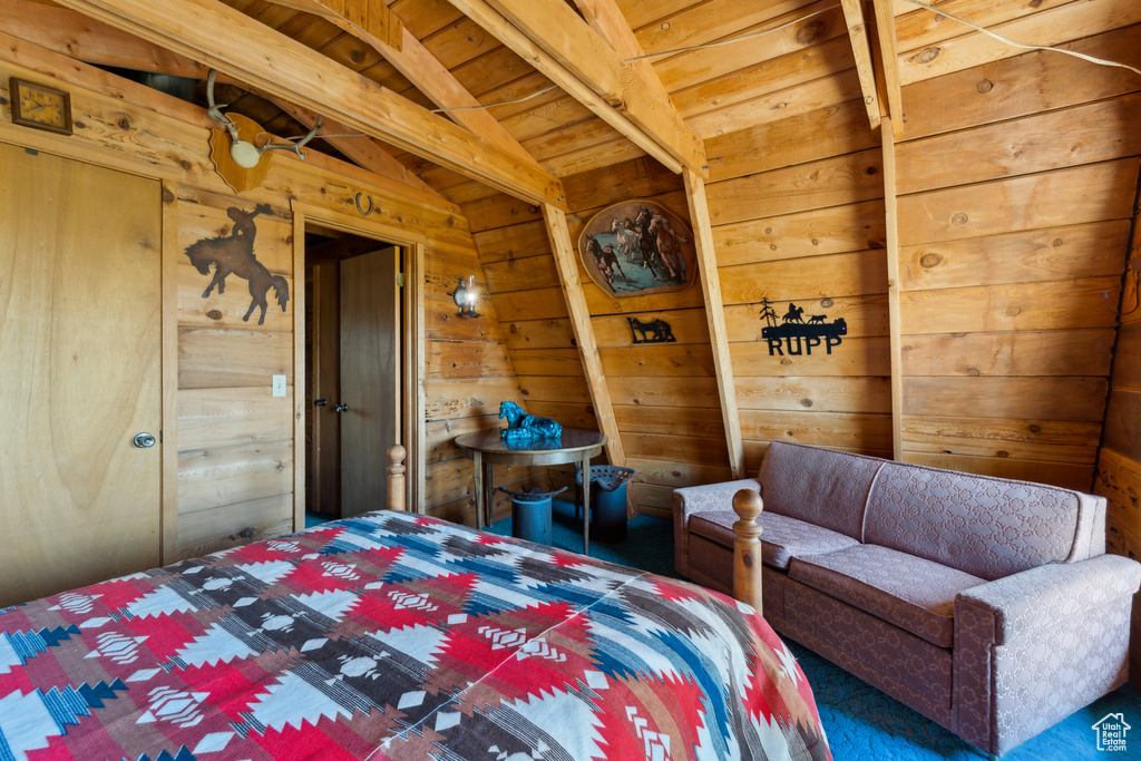 Bedroom with wood walls, carpet floors, and wood ceiling with exposed beams