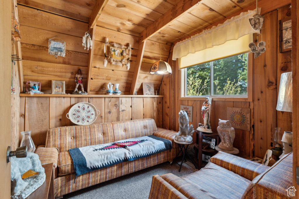 Living area with wood walls, carpet floors, and wood ceiling with exposed beams