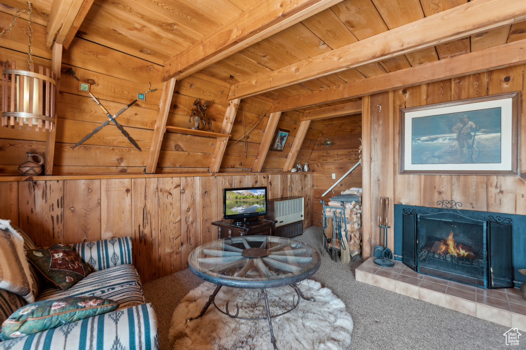 Living room with carpet flooring, wood walls, wooden ceiling, and a fireplace