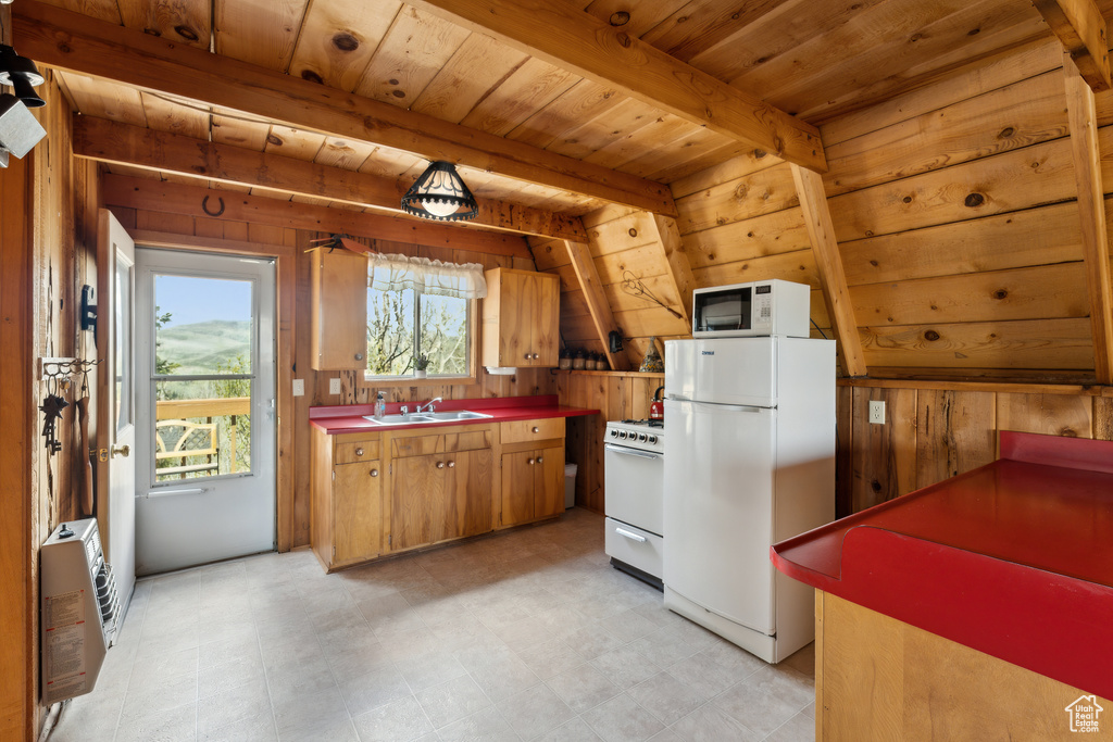 Kitchen with white appliances, heating unit, wooden walls, wood ceiling with exposed beams, and a sink