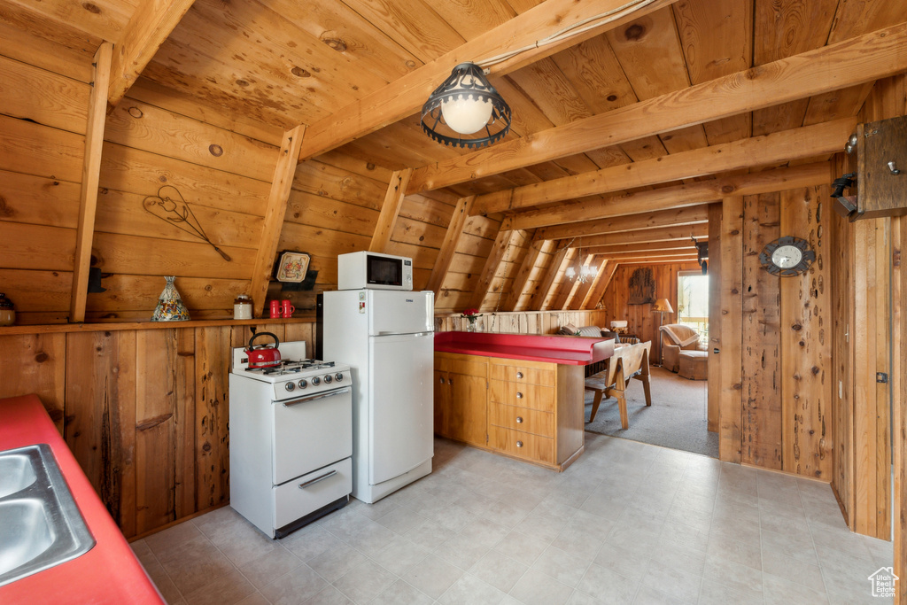Kitchen featuring white appliances, wooden walls, wooden ceiling with exposed beams, light flooring, and a sink