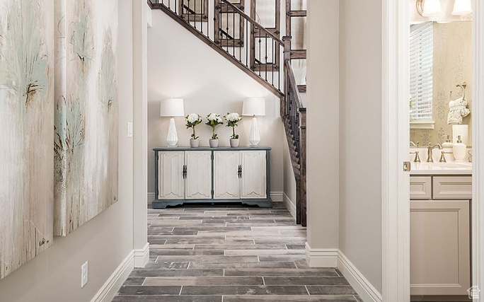 Hall featuring wood finished floors, stairway, baseboards, and a sink