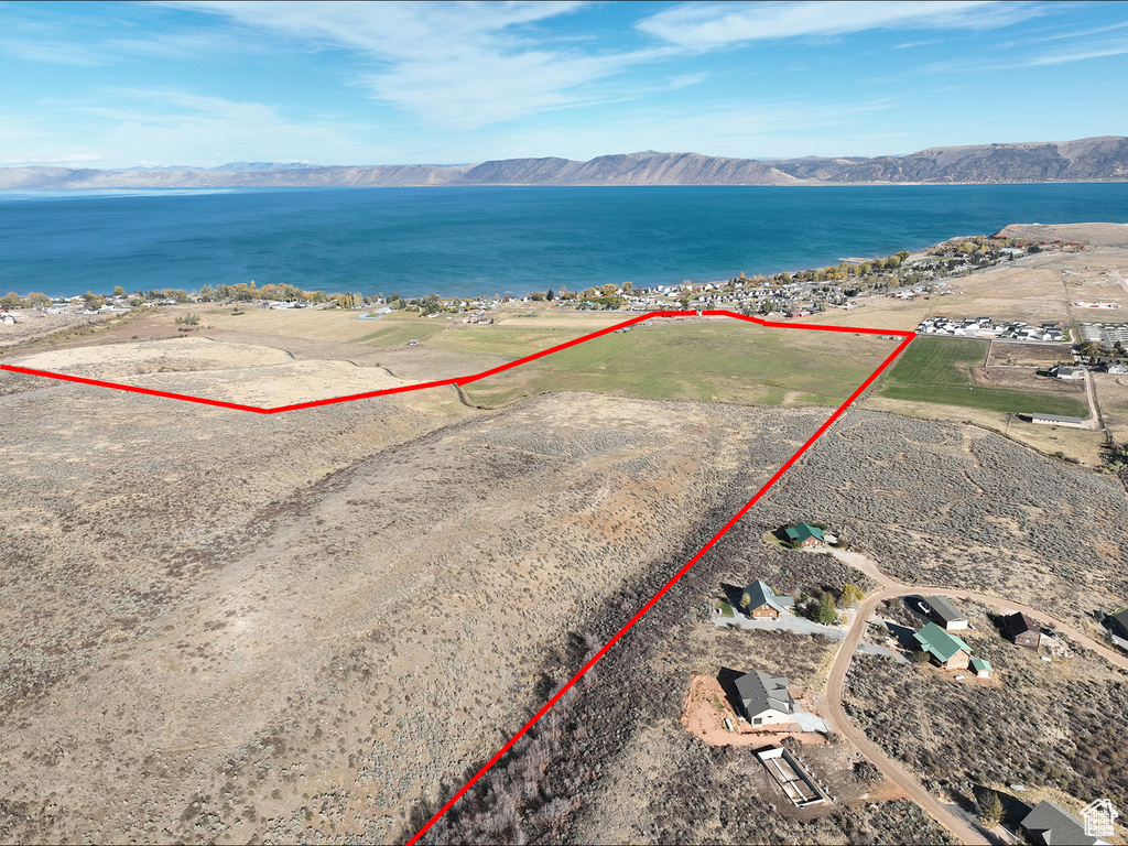 Aerial view of property and surrounding area with a water and mountain view and property parcel outlined