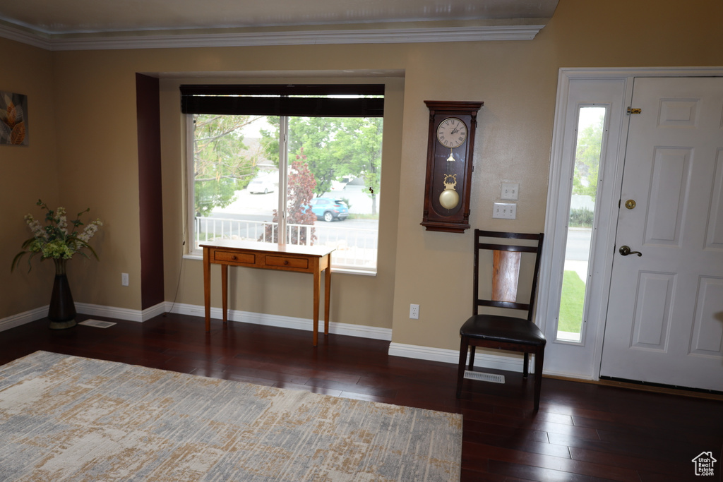 Foyer entrance featuring wood-type flooring, crown molding, and baseboards