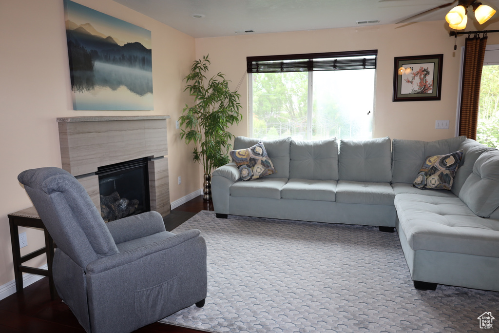 Living room featuring a fireplace, baseboards, and ceiling fan
