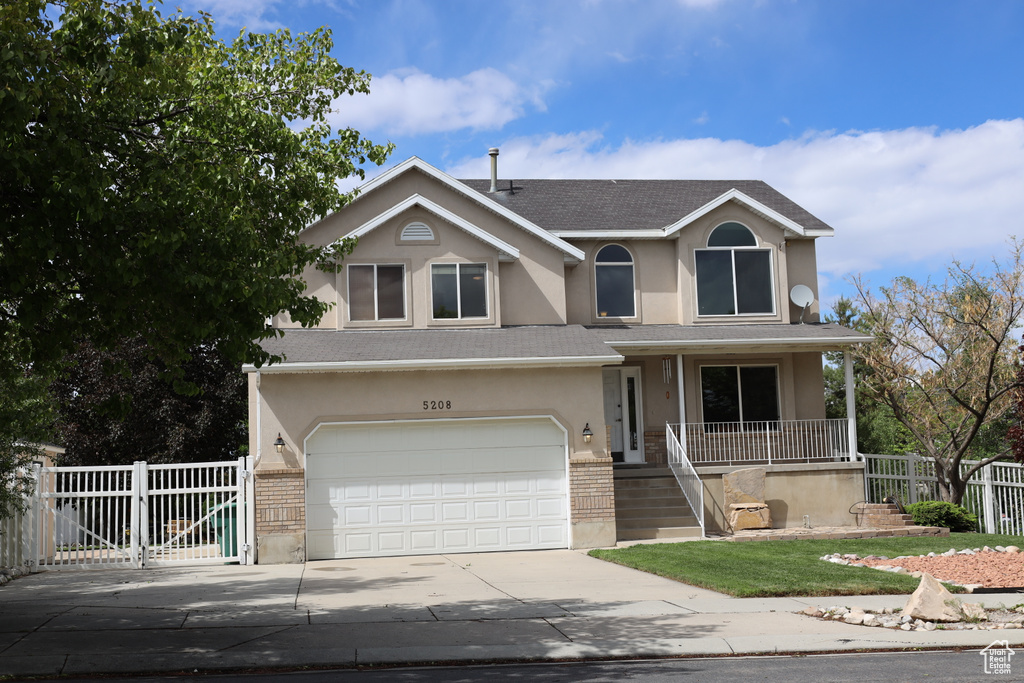 Traditional home featuring stucco siding, concrete driveway, an attached garage, a porch, and roof with shingles