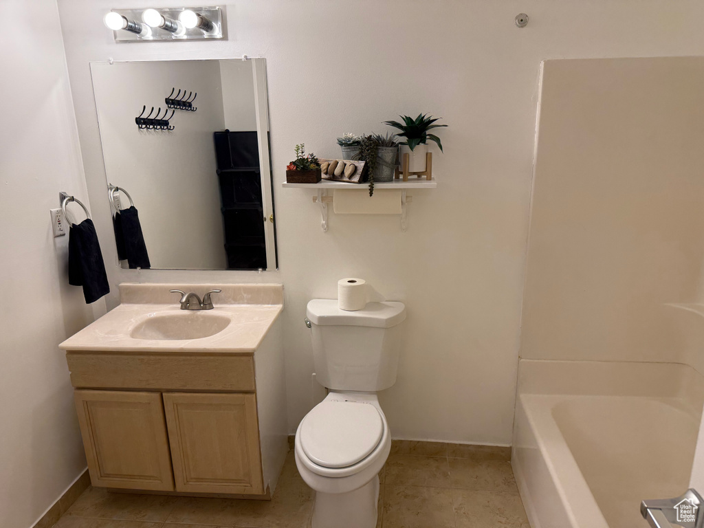 Bathroom with toilet, a tub, vanity, baseboards, and tile patterned flooring