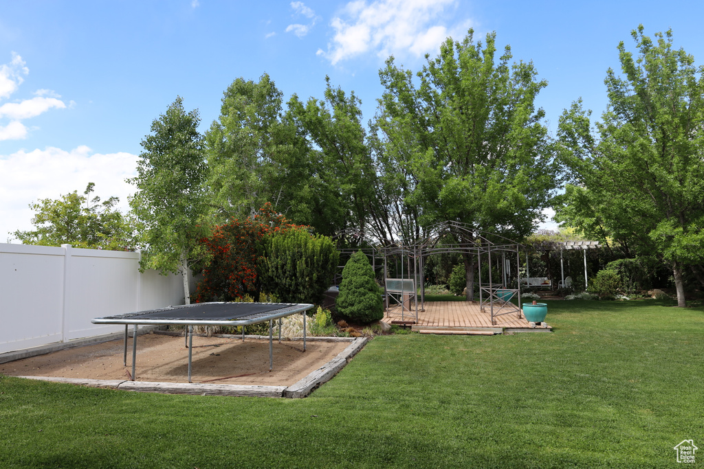 View of yard with a deck and a trampoline