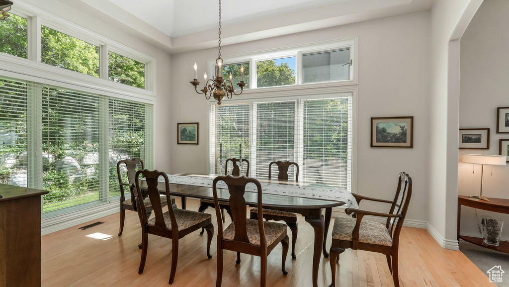 Dining area with arched walkways, light wood-style floors, a towering ceiling, a chandelier, and baseboards