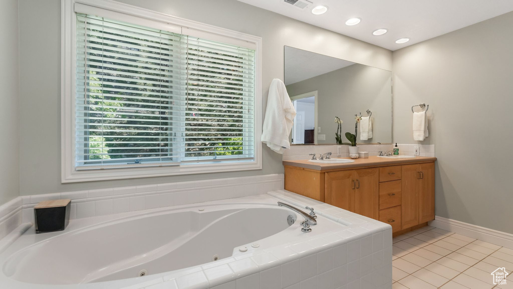 Bathroom featuring a whirlpool tub, double vanity, plenty of natural light, and tile patterned floors