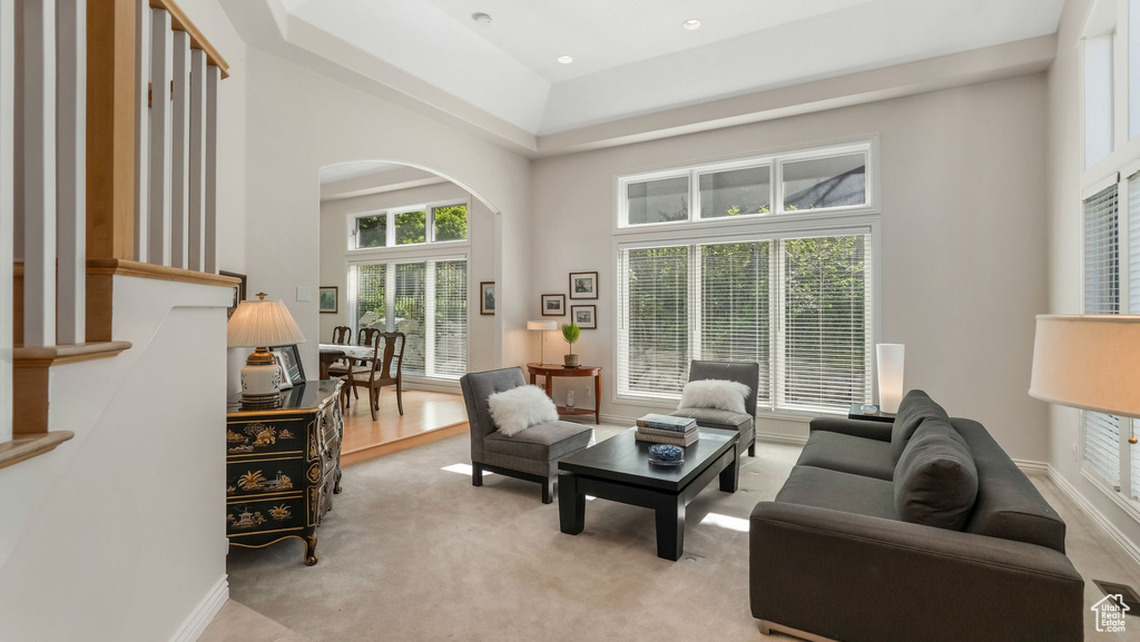 Living area with arched walkways, light colored carpet, a towering ceiling, and recessed lighting