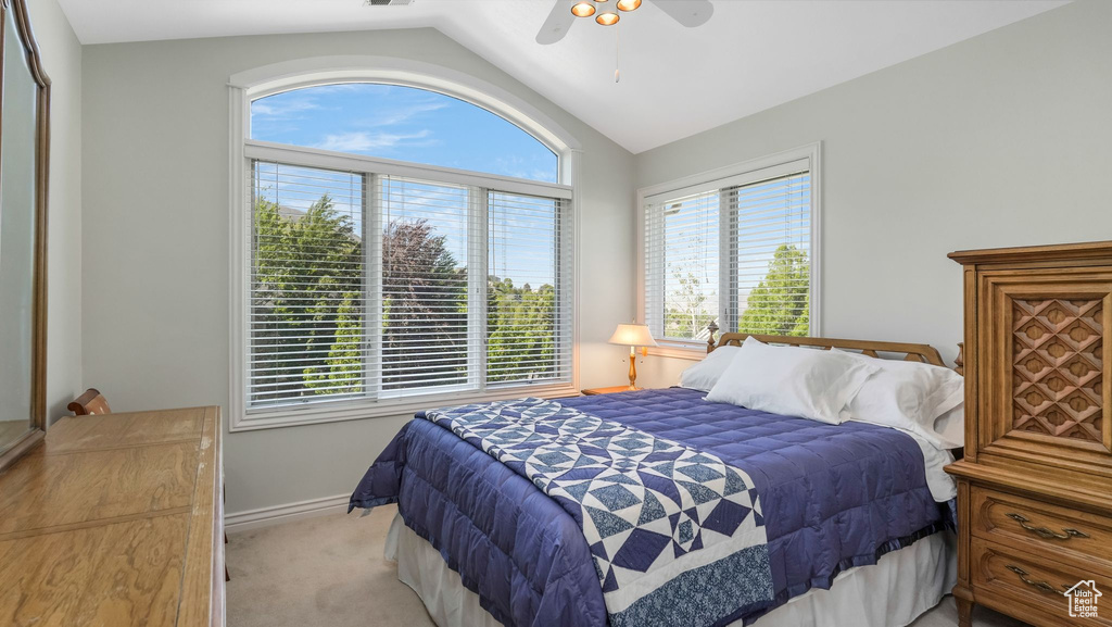 Bedroom with vaulted ceiling, light carpet, ceiling fan, and baseboards