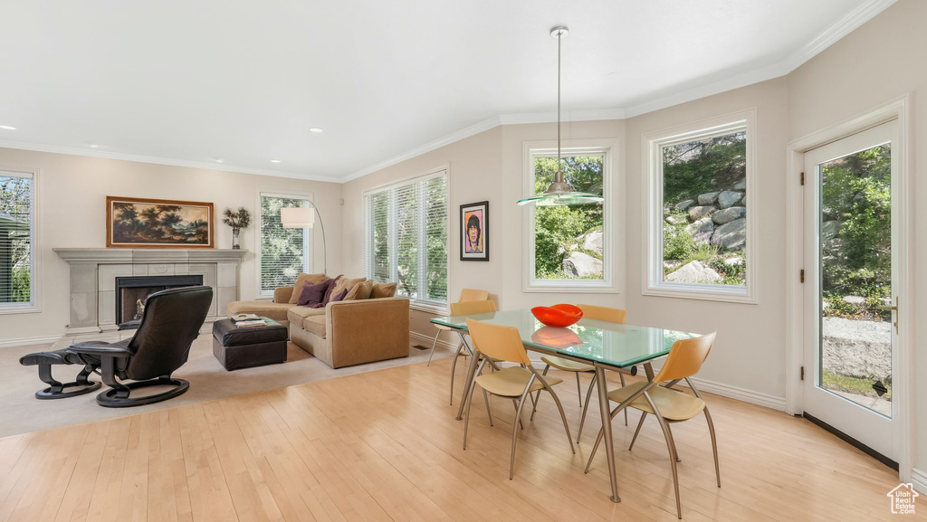 Dining room with light wood-style flooring, a fireplace, baseboards, recessed lighting, and ornamental molding