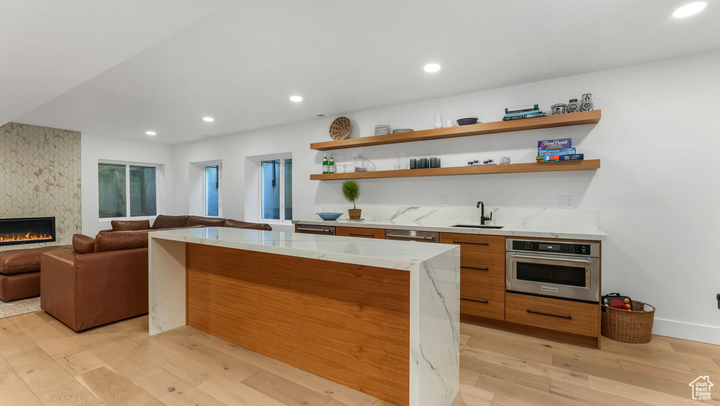 Kitchen with oven, modern cabinets, light wood-style flooring, open shelves, and open floor plan