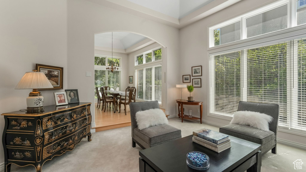 Living area featuring arched walkways, a towering ceiling, healthy amount of natural light, light carpet, and a chandelier