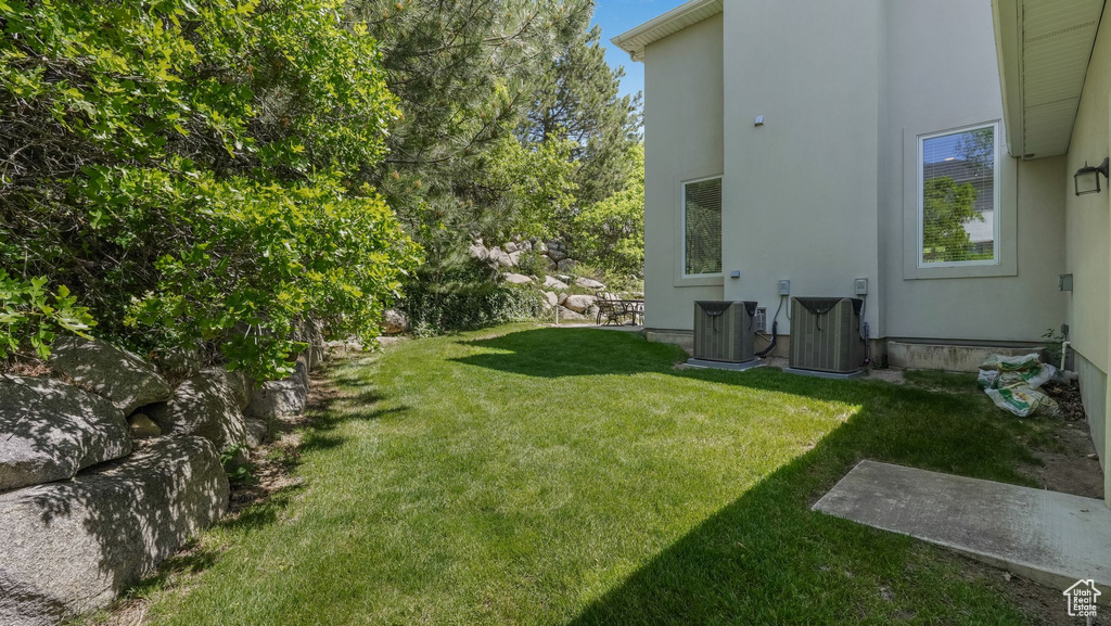 View of green lawn featuring central air condition unit