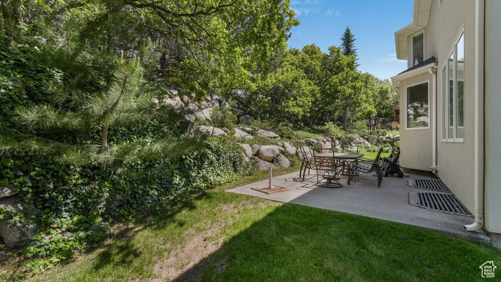 View of grassy yard with a patio area