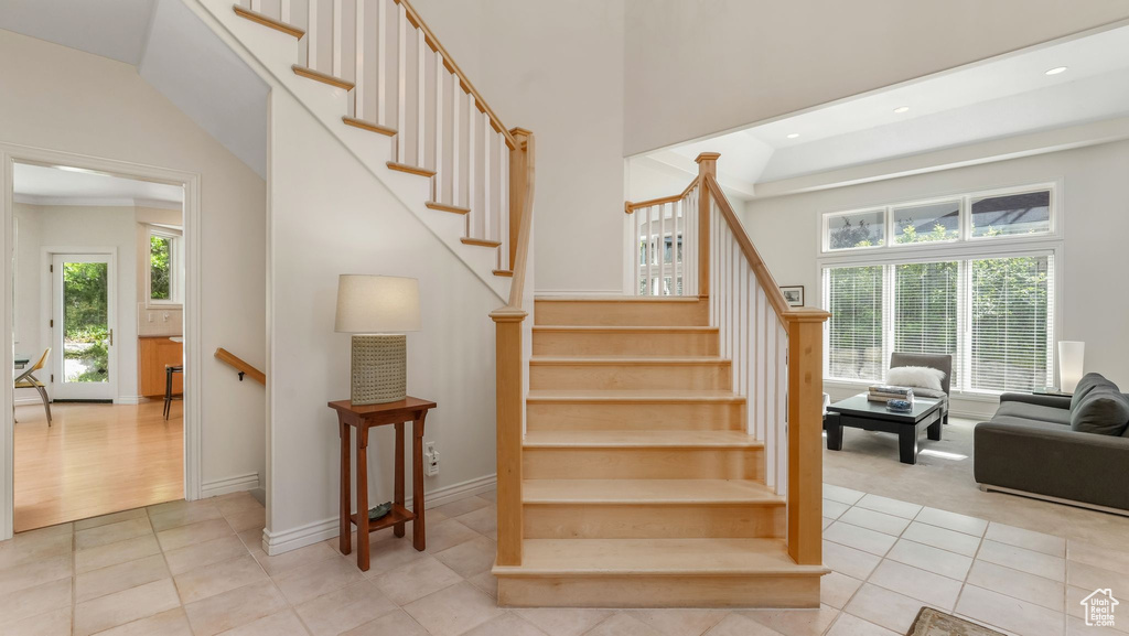 Staircase featuring tile patterned floors, recessed lighting, a towering ceiling, and baseboards