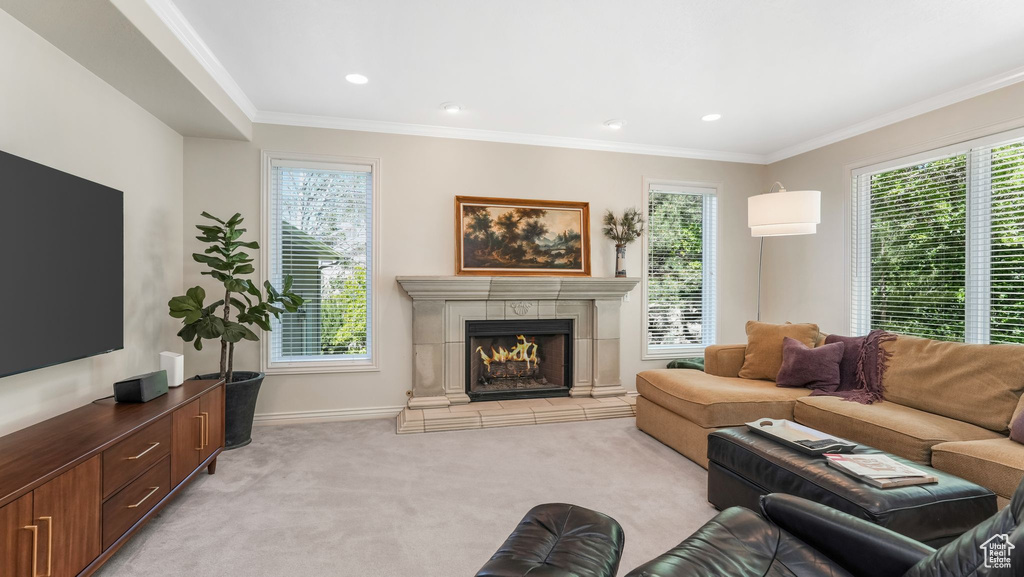 Living area featuring light carpet, a tile fireplace, crown molding, and baseboards