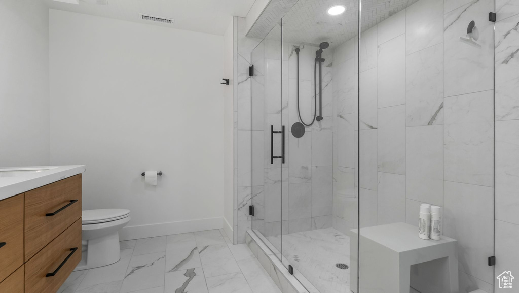 Bathroom featuring toilet, vanity, a marble finish shower, marble finish floors, and baseboards