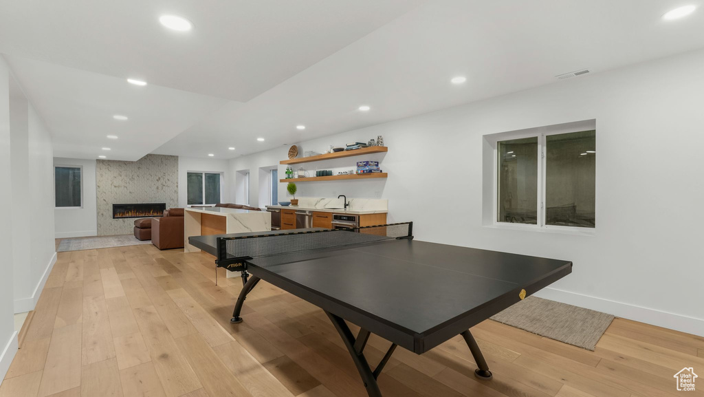 Playroom featuring recessed lighting, light wood finished floors, baseboards, a large fireplace, and a sink