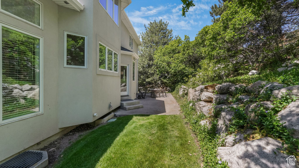 View of green lawn featuring a patio and entry steps