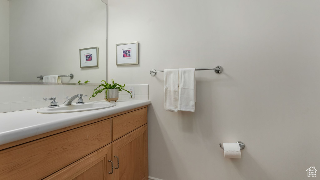 Bathroom featuring vanity, backsplash, and baseboards