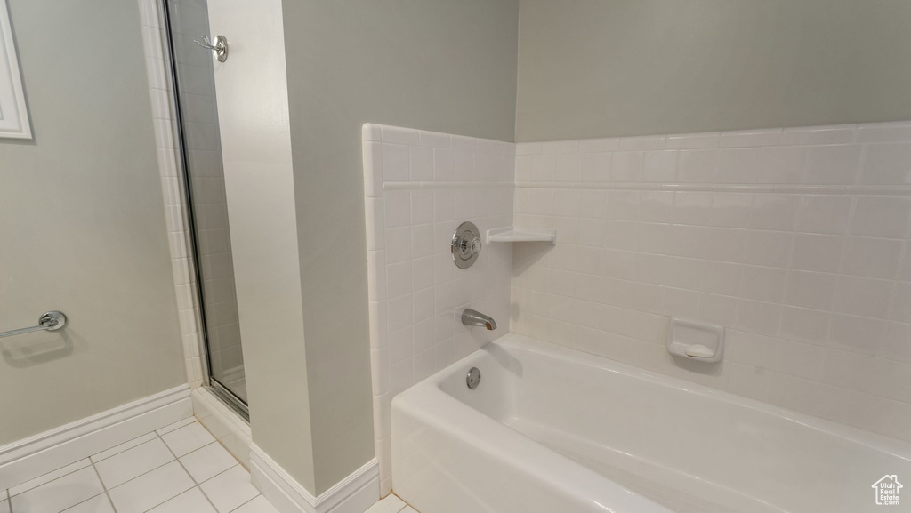 Bathroom with a shower, tile patterned floors, baseboards, and a bath