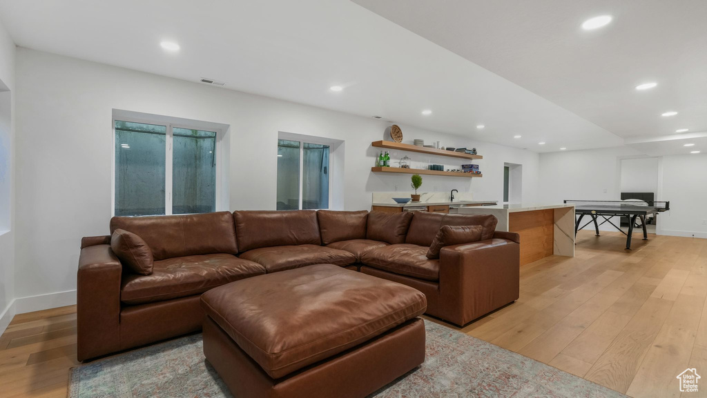 Living room featuring light wood-style flooring, recessed lighting, baseboards, and bar