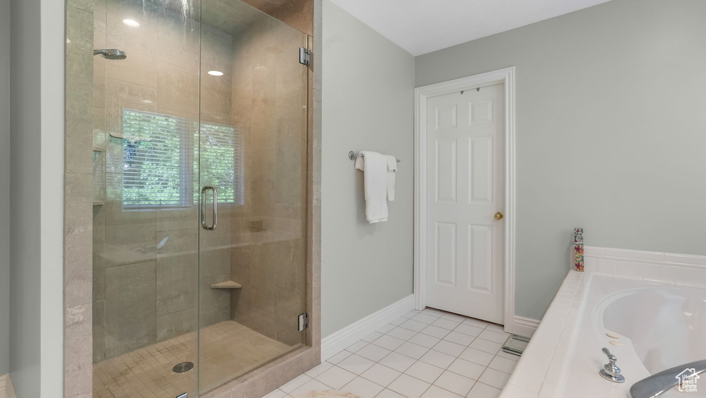 Bathroom featuring tile patterned flooring, a stall shower, a bath, and baseboards