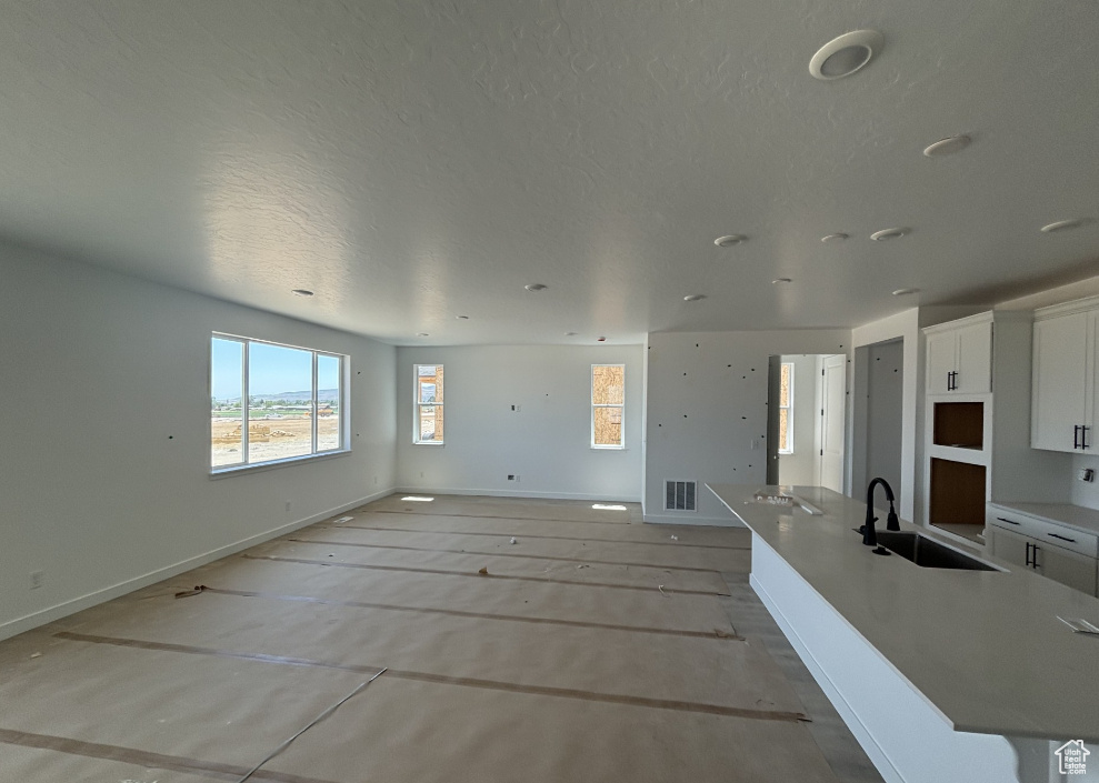 Unfurnished living room with a sink and a textured ceiling