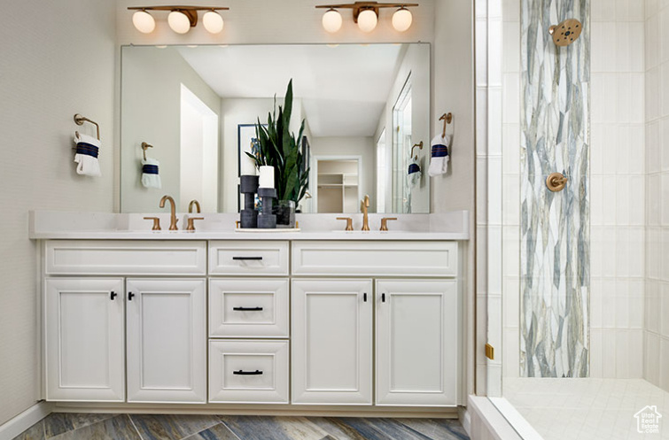 Bathroom featuring tiled shower and double vanity