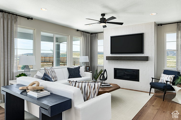 Living room with wood finished floors, a ceiling fan, a fireplace, recessed lighting, and baseboards