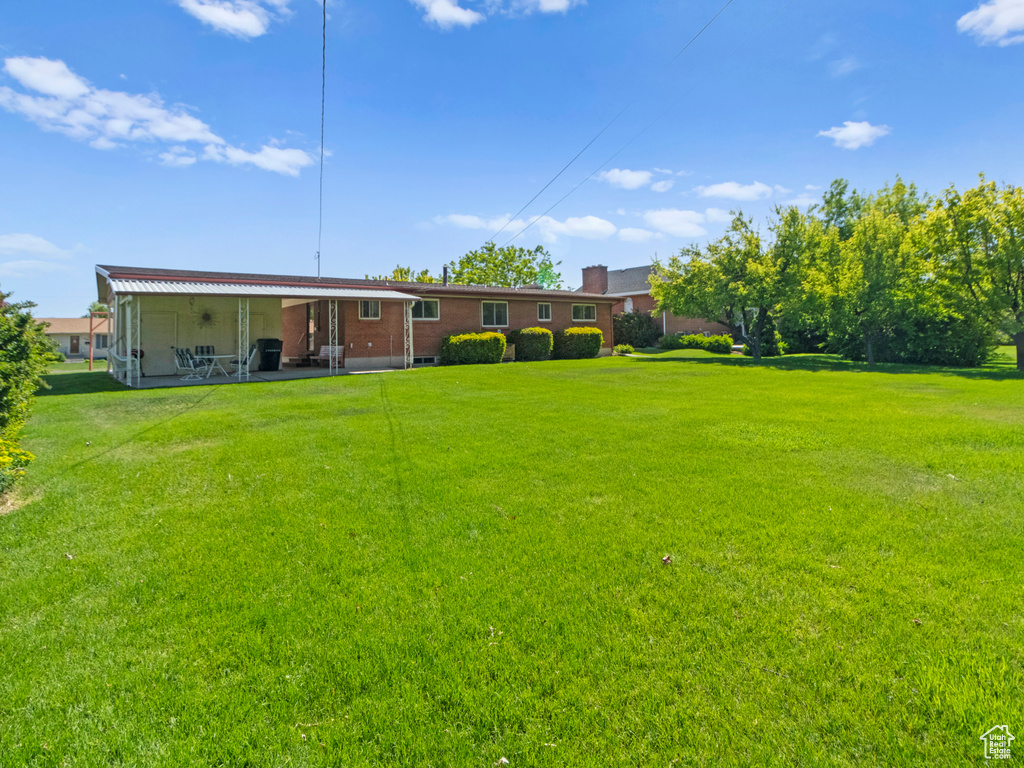 View of grassy yard featuring a patio area