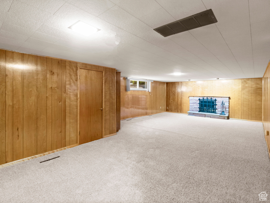 Below grade area with wooden walls, carpet flooring, and a fireplace with raised hearth