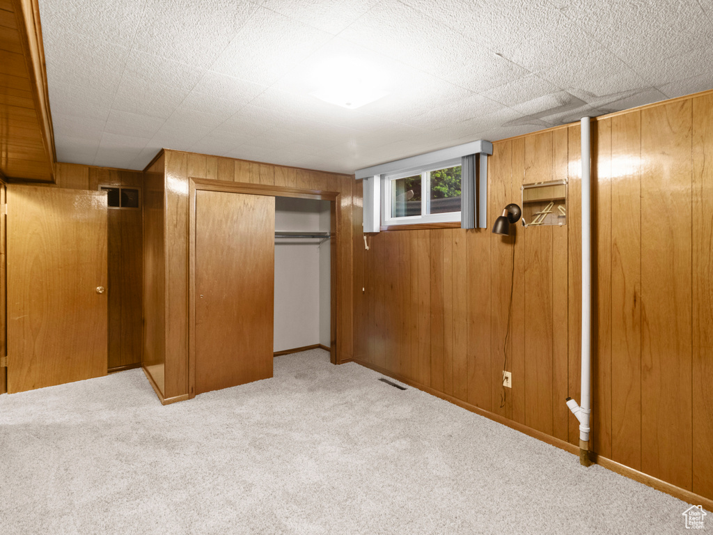 Unfurnished bedroom featuring carpet flooring, wooden walls, and a closet
