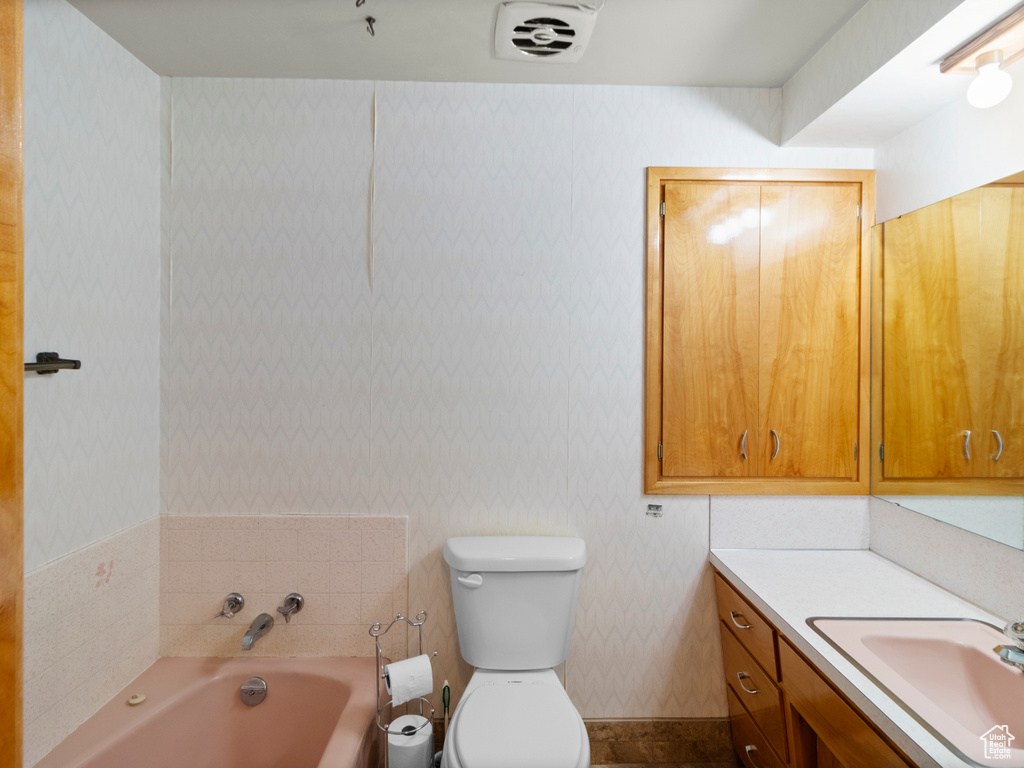 Full bathroom with a garden tub, vanity, toilet, and wallpapered walls
