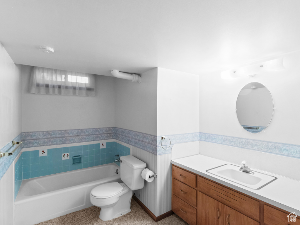Bathroom with a garden tub, toilet, vanity, and a wainscoted wall