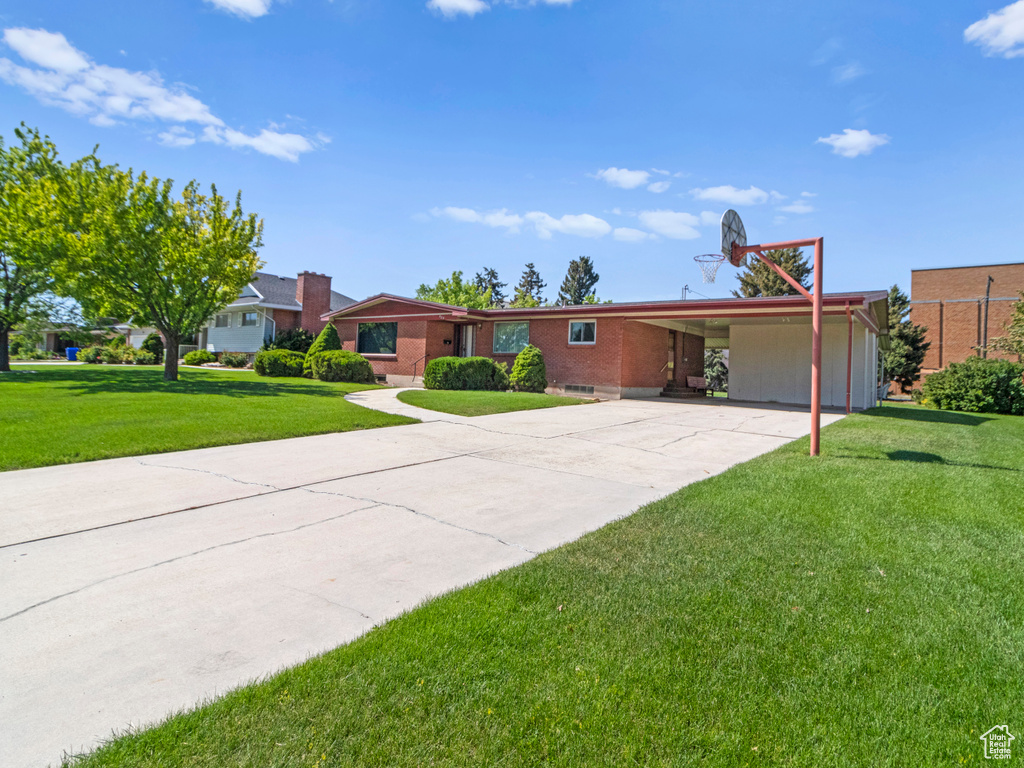 View of front of house featuring a carport, a front lawn, concrete driveway, and brick siding