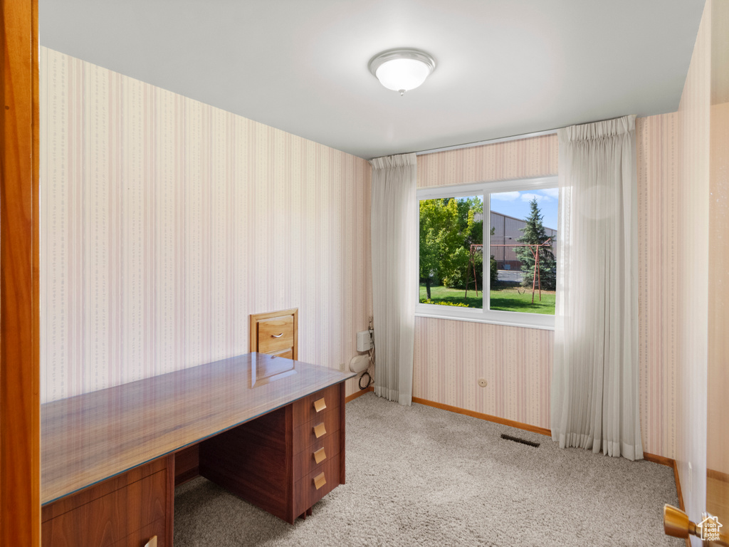 Home office featuring wallpapered walls, light colored carpet, and baseboards