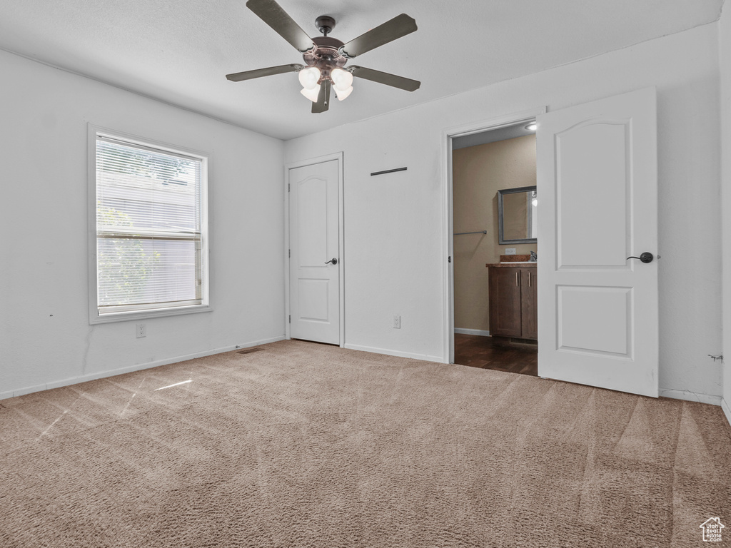 Unfurnished bedroom with carpet, ensuite bath, baseboards, and a ceiling fan